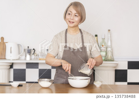 キッチンでアメリカンワッフルを焼くシニア女性 135738488