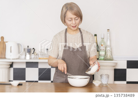 キッチンでアメリカンワッフルを焼くシニア女性 135738489