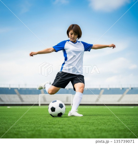 サッカー場でボールを蹴ろうとしているサッカーの女子選手 135739071