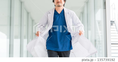 病院の通路を歩く白衣を着た男性医師 135739192