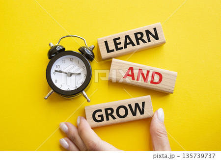 Learn and grow symbol. Concept words Learn and grow on wooden blocks. Businessman hand. Beautiful yellow background with alarm clock. Business and Learn and grow concept. Copy space. Learn and grow symbol. Concept words Learn and grow on wooden blocks. Businessman hand. Beautiful yellow background with alarm clock. Business and Learn and grow concept. Copy space. 135739737