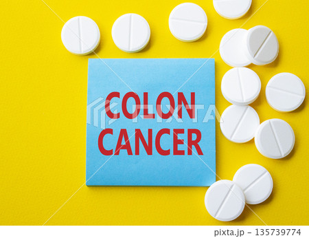 Colon Cancer symbol. Concept word Colon Cancer on blue note. Beautiful yellow background with pills. Medicine and Colon Cancer concept. Copy space 135739774