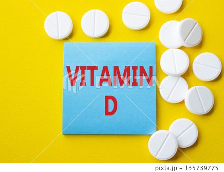 Vitamin D symbol. Concept word Vitamin D on blue note. Beautiful yellow background with pills. Medicine and Vitamin D concept. Copy space 135739775