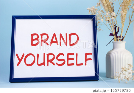 Brand yourself symbol. Concept words Brand yourself on beautiful wooden picture frame. Beautiful light blue background with flower vase. Business and Brand yourself concept. Copy space. 135739780