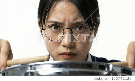 汗をにじませる真剣な女子高生ドラマーの表情（ドラム越しアップ） 135741126