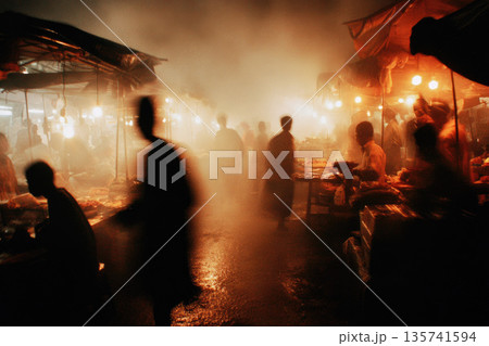 Busy wet market stall scene with people moving through misty air illuminated by warm lights creating lively and atmospheric environment at night Busy wet market stall scene with people moving through misty air illuminated by warm lights creating lively and atmospheric environment at night 135741594