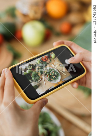 A person is taking a picture of a healthy salad with fresh ingredients using their mobile phone camera A person is taking a picture of a healthy salad with fresh ingredients using their mobile phone camera 135742662
