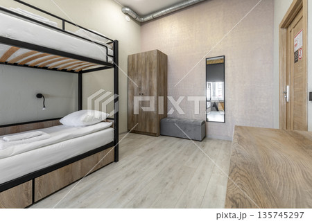 Hostel dormitory room with black metal bunk bed and wooden wardrobe Hostel dormitory room with black metal bunk bed and wooden wardrobe 135745297