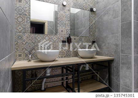 Modern hostel shared bathroom with double vessel sinks and patterned tiles Modern hostel shared bathroom with double vessel sinks and patterned tiles 135745301