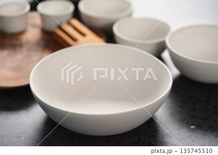 Empty matt white ceramic handmade tableware set on concrete countertop Empty matt white ceramic handmade tableware set on concrete countertop 135745510