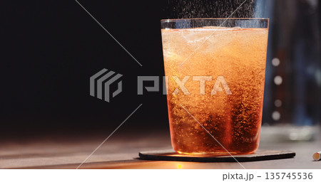 pour syrup in tonic in tumbler glass on walnut table pour syrup in tonic in tumbler glass on walnut table 135745536
