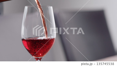 pour red wine into wineglass dining room on background 135745538