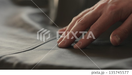 closeup man hand checking seam on soft gray leather clothes closeup man hand checking seam on soft gray leather clothes 135745577