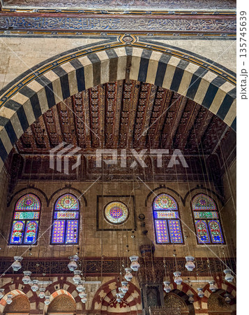 Interior view of Sultan Al-Ashraf Qaytbay Mosque and mausoleum. Features intricate arches, striped wall, and decorative dome. Soft light filters through stained glass window Interior view of Sultan Al-Ashraf Qaytbay Mosque and mausoleum. Features intricate arches, striped wall, and decorative dome. Soft light filters through stained glass window 135745639