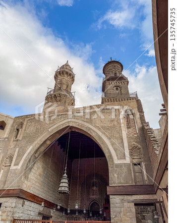 Qalawun complex interior at Al-Muizz Street in Cairo. Features Islamic architecture with arches, intricate designs, and a central courtyard with greenery. 135745735