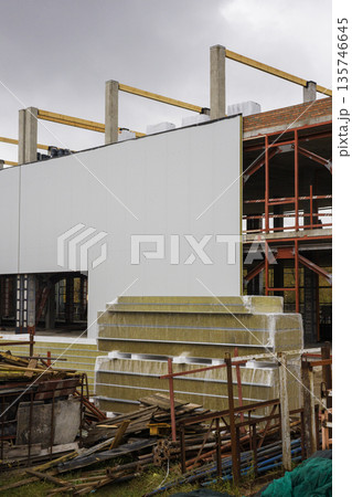 Workers are busy at a construction site with a new building taking shape. Materials are arranged nearby as work continues in the area Workers are busy at a construction site with a new building taking shape. Materials are arranged nearby as work continues in the area 135746645