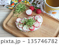 Slice of sourdough bread with slices of fresh radish on the cutting board. 135746782
