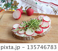 Slice of sourdough bread with slices of fresh radish on the cutting board. 135746783