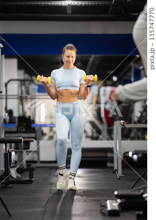 Woman exercising with dumbbells in fitness gym Woman exercising with dumbbells in fitness gym 135747770