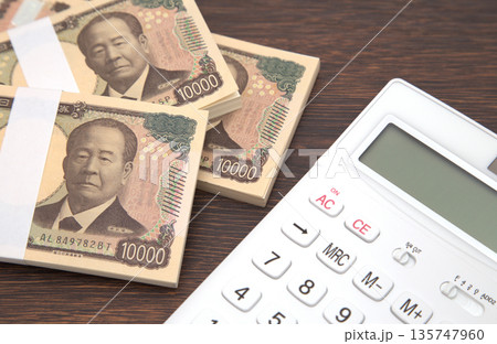 机の上に置かれたお金と電卓 机の上に置かれたお金と電卓 135747960