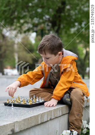 Boy playing chess outdoor. Learning strategic game. Education. Boy playing chess outdoor. Learning strategic game. Education. 135749329