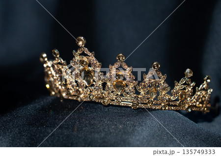 Golden yellow crown with citrines, gemstones on dark background Golden yellow crown with citrines, gemstones on dark background 135749333
