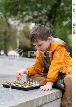 Boy playing chess outdoor. Learning strategic game. Education. Boy playing chess outdoor. Learning strategic game. Education. 135749401