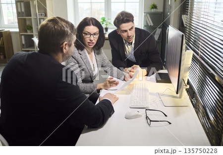 Colleagues analyzing finance data together at computer during office meeting 135750228