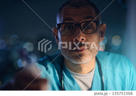 Male medic wearing scrubs working during night shift Male medic wearing scrubs working during night shift 135751508