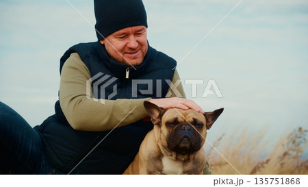 A person enjoying a serene moment with a relaxed French Bulldog in the great outdoors, showcasing the bond between humans and their canine companions amidst natural beauty and tranquility. A person enjoying a serene moment with a relaxed French Bulldog in the great outdoors, showcasing the bond between humans and their canine companions amidst natural beauty and tranquility. 135751868