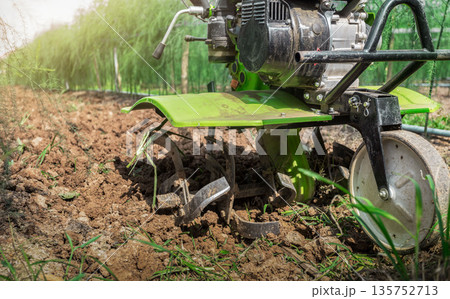 Farmer with ploughs ground in sunny day.  preparing land with seedbed cultivator as part of pre seeding activities in early spring season of agricultural works at farmlands. 135752713