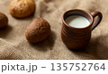 Rustic still life with fresh milk in clay mug and homemade buns on burlap background, selective focus. 135752764