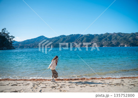 冬に海辺を歩く若い女性 135752800