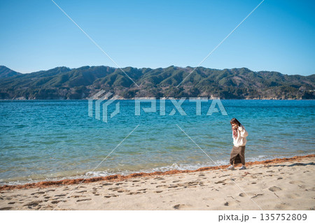 冬に海辺を歩く若い女性 135752809