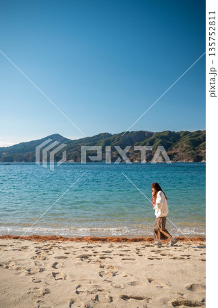 冬に海辺を歩く若い女性 135752811
