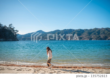 冬に海辺を歩く若い女性 135752813