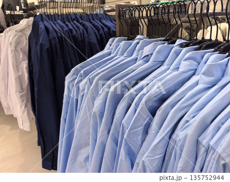 Variety of neatly arranged dress shirts in a modern clothing store display 135752944