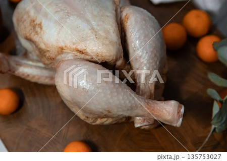 Raw young whole chicken on wooden board with oranges, ready for cooking and seasoning concept. Holiday meal preparation. 135753027