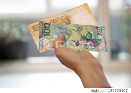Woman holding 100 hundred new ruble banknote. Russian cash money as symbol of finance and payment. Macro shot of currency. Woman holding 100 hundred new ruble banknote. Russian cash money as symbol of finance and payment. Macro shot of currency. 135753107
