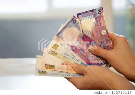 Woman holding a fan of Hong Kong dollar banknotes. Cash payment concept, finance, and wealth management for budgeting. 135753117