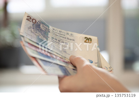 Woman holding Hong Kong twenty dollar banknotes. Financial transaction concept. Currency exchange and travel budget planning. 135753119
