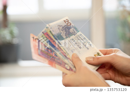 Woman holding a fan of Hong Kong dollar banknotes. Financial transaction and personal finance concept. Money exchange for traveler income. Woman holding a fan of Hong Kong dollar banknotes. Financial transaction and personal finance concept. Money exchange for traveler income. 135753120