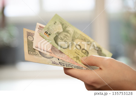 Woman s hand holding variety of international currency banknotes. Concept of travel budget, foreign exchange, or global finance for business. Woman s hand holding variety of international currency banknotes. Concept of travel budget, foreign exchange, or global finance for business. 135753128