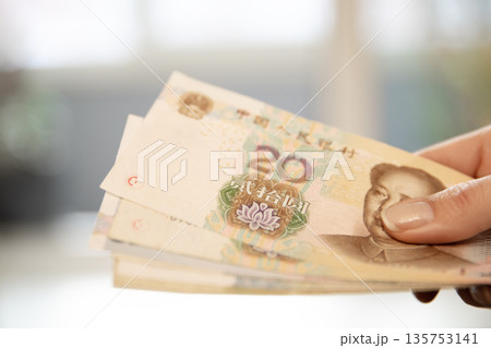 Woman holding a stack of twenty renminbi banknotes. Chinese yuan currency for finance, trade, economy, or travel concept. Woman holding a stack of twenty renminbi banknotes. Chinese yuan currency for finance, trade, economy, or travel concept. 135753141