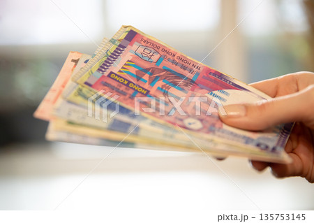 Woman holding a stack of Hong Kong dollar banknotes. Financial transaction and Asian currency exchange concept. Saving money and banking. Woman holding a stack of Hong Kong dollar banknotes. Financial transaction and Asian currency exchange concept. Saving money and banking. 135753145