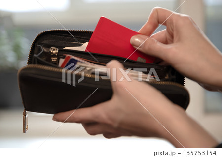 Woman taking red credit card out of wallet. Financial transaction concept. Retail shopping, personal finance, and payment method image. Woman taking red credit card out of wallet. Financial transaction concept. Retail shopping, personal finance, and payment method image. 135753154