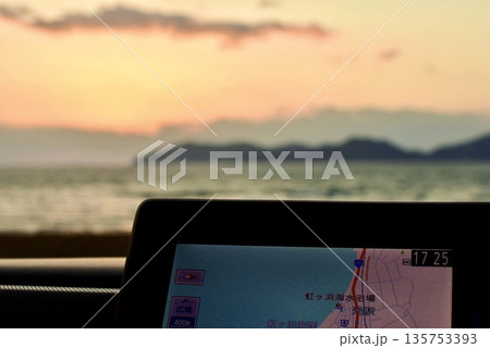 車内のカーナビとそこから夕暮れの海岸 車内のカーナビとそこから夕暮れの海岸 135753393