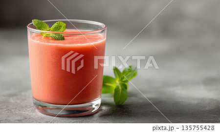 Fresh guava smoothie in a transparent glass with mint, natural fruit juice on a minimalist gray background 135755428