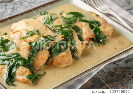 Close-up of Florentine chicken fried and then braised in a creamy wine sauce with spinach in a plate. Horizontal Close-up of Florentine chicken fried and then braised in a creamy wine sauce with spinach in a plate. Horizontal 135756093