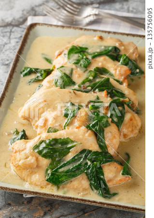 Chicken Florentine is a classic dish consisting of fried chicken fillet and spinach, served with a creamy sauce, close-up on a plate. Vertical 135756095